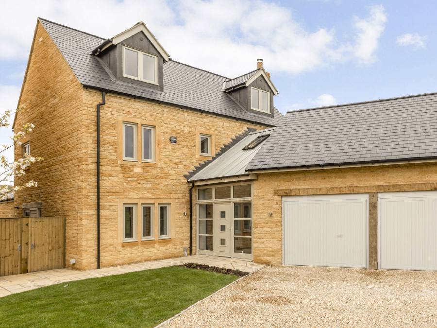 The front view of Milburn House a Cotswold stone cottage in Chipping Campden which is part of the Cricket Green development. Showing the front door and double garage.