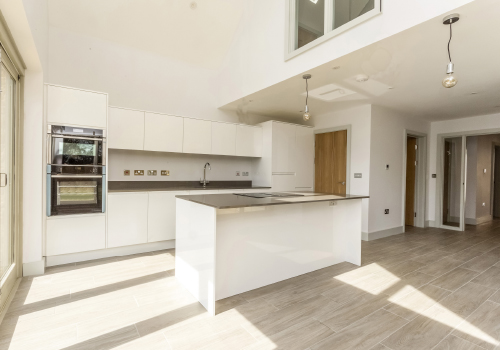 A modern white kitchen with built in oven and central island.