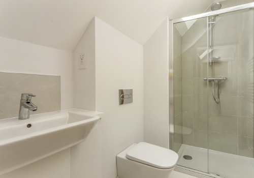 A white bathroom includes a view of the sink, toilet and shower